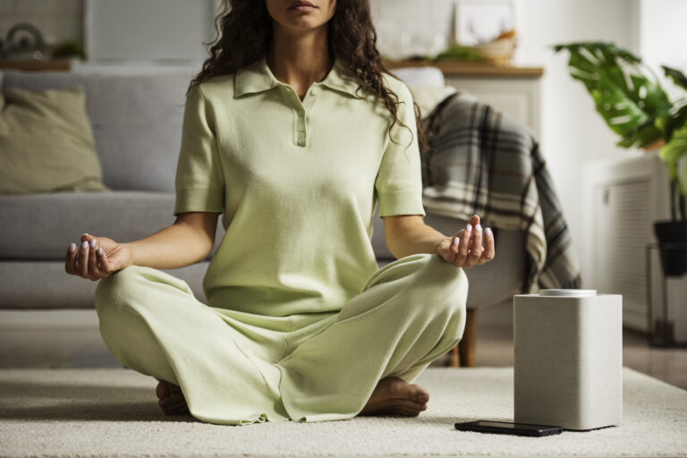 front-view-woman-meditating-with-smart-speaker