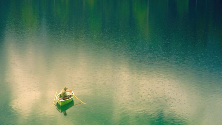 man in red shirt riding on boat on body of water during daytime